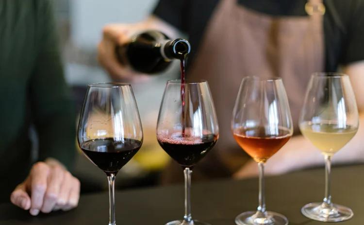 pouring different wines into the glasses arranged for the wine tasting on the counter